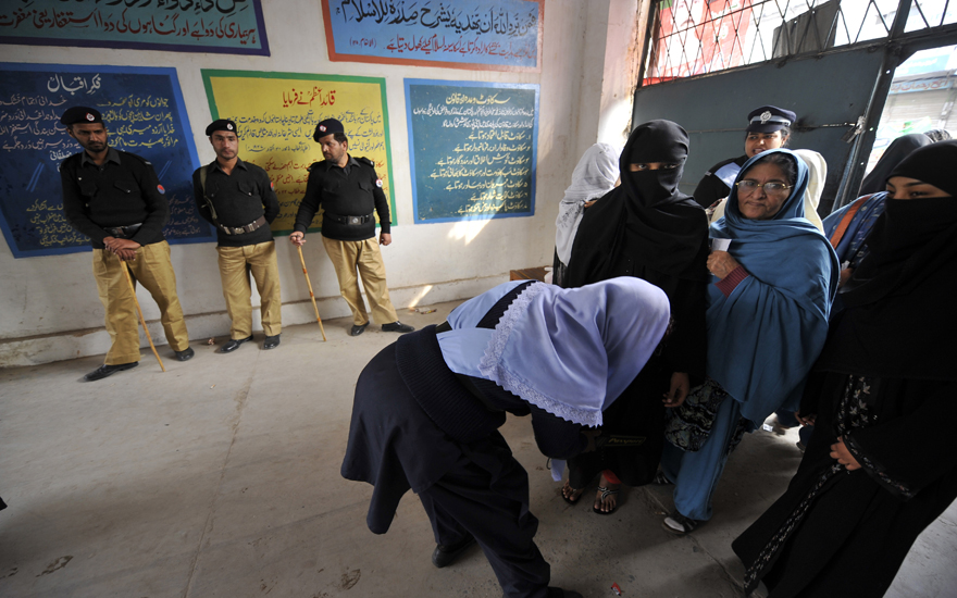 A Pakistani police officer searches women entering a polling station during a by-election in Rawalpindi on February 24, 2010. More than 20 candidates contested in the by-election to fill the seat which fell vacant after the resignation of an MP from Rawalpindi, just outside the Pakistani capital Islamabad. The Pakistan People's Party (PPP) of assassinated former premier Benazir Bhutto came into power after winning the general elections in February 2008. AFP PHOTO/ AAMIR QURESHI