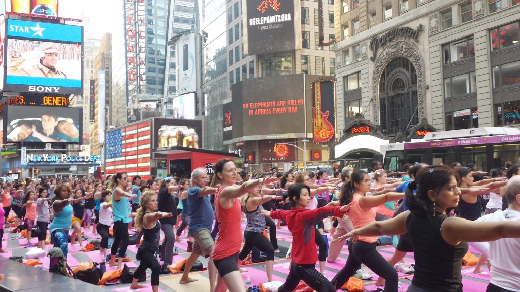 People perform yoga exercises on June 20, 2016 on Times Square in New York City. Yogis from throughout the world travel every year to Times Square to celebrate the Summer Solstice with free yoga classes in the heart of New York City, on what is the Northern HemisphereÃ­s longest day of the year. / AFP PHOTO / Brigitte DUSSEAU