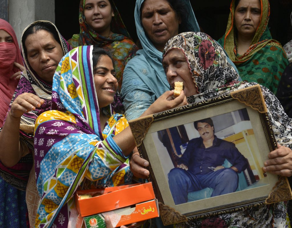Relatives of Pakistani national, Zulfiqar Ali, who was convicted to death in 2005 for heroin possession, hold his photograph as they share sweets in celebration after the Indonesian government halted his execution, in Lahore on July 29, 2016. Indonesia executed four drug convicts July 29, but 10 others due to face the firing squad were given an apparent reprieve in a confused process one lawyer condemned as a "complete mess". The first reprieved was Pakistani Zulfiqar Ali, whom rights groups say was beaten into confessing to heroin possession, leading to his 2005 death sentence. / AFP PHOTO / ARIF ALI