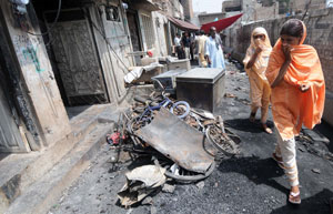 A woman walks past burnt out buildings in Gojra after accusations of blasphemy led to mob violence. Photo: AFP / File