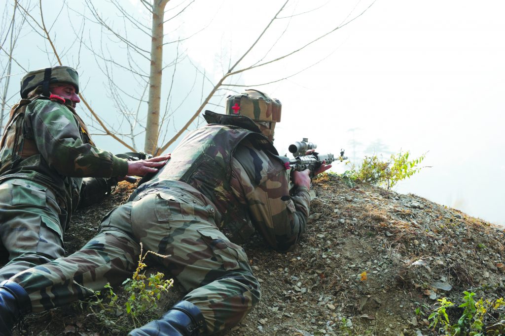 Indian soldiers look on from their position by a road overlooking army barracks following an attack by militants on the camp in Gingal Uri, some 90 kms north of Srinagar near the Line of Control (LoC), on December 5, 2014. Militants hurling grenades stormed an army camp in Indian Kashmir and killed 11 security officials, police said, ratcheting up violence in the Muslim-majority region which is voting in state elections. Six of the attackers also died in the shootout at the sprawling army camp in Uri, near the heavily militarised Line of Control (LoC) dividing the disputed Himalayan territory between India and Pakistan, an Indian police official told AFP. AFP PHOTO/Rouf BHAT / AFP PHOTO / ROUF BHAT