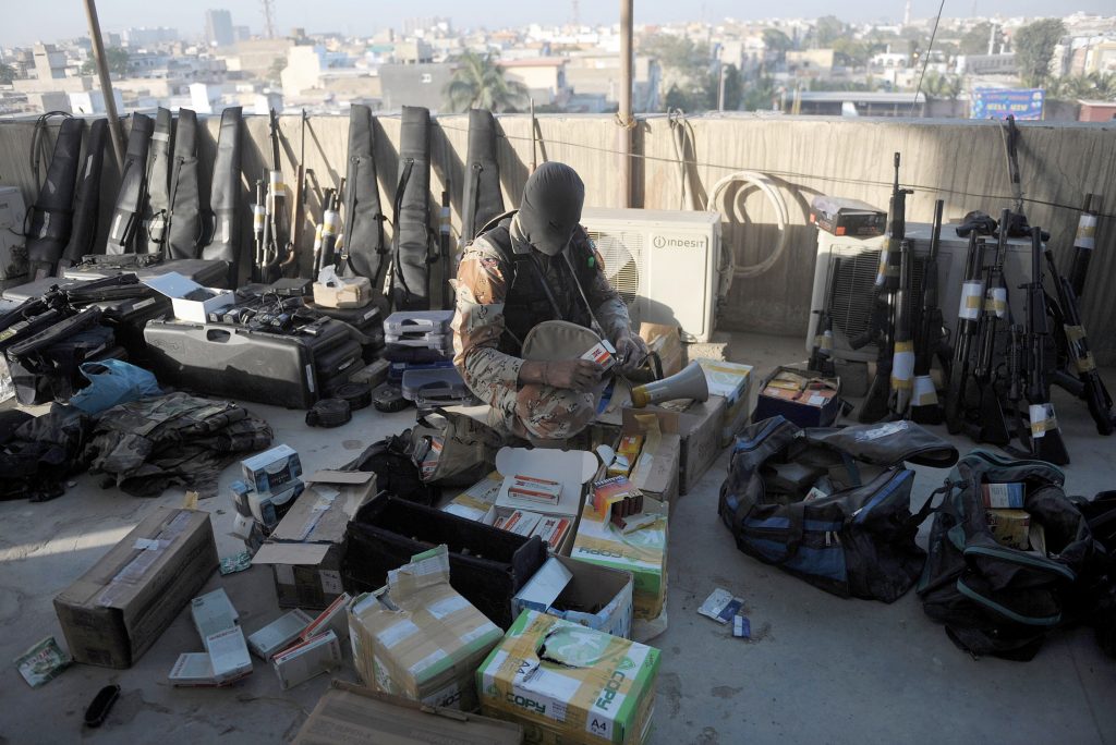 A Pakistani paramilitary soldier inspects weapons recovered following a raid on the offices of the MQM